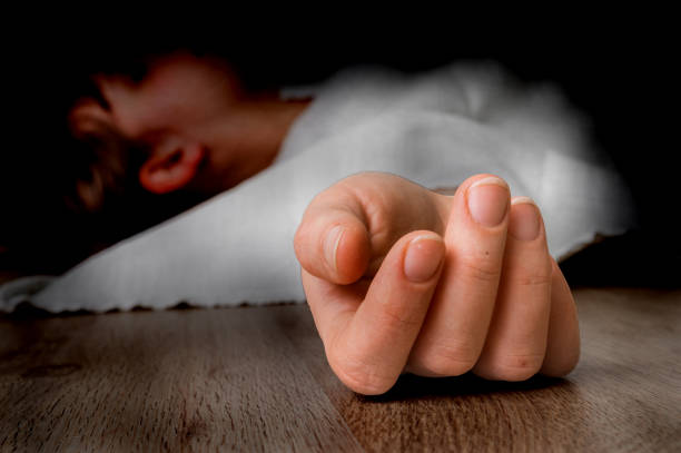 Dead woman lying on the floor under white cloth with focus on hand